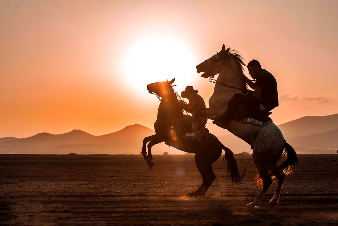 Silhouetted horseback riders performing at sunset in the scenic landscape of Kayseri, Turkey.